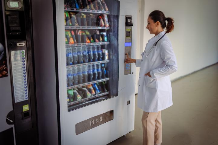 Imagen de archivo de una doctora comprando algo en una máquina expendedora en el pasillo de un hospital.
