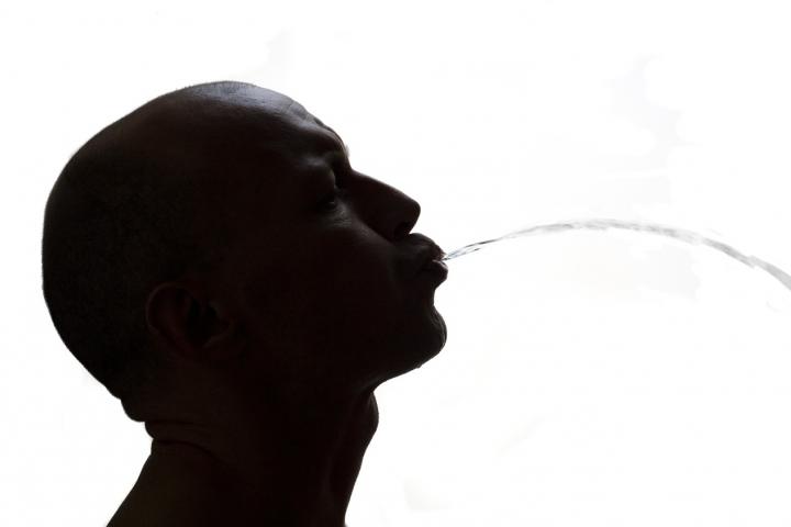 La silueta de un hombre escupiendo en la calle.