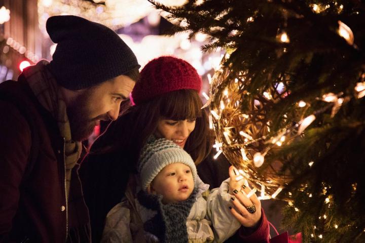 Los padres muestran a su hijo las luces navideñas del árbol de Navidad en el centro de la ciudad