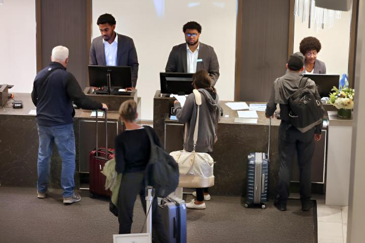 Varios huéspedes esperando a ser atendidos en la recepción de un hotel