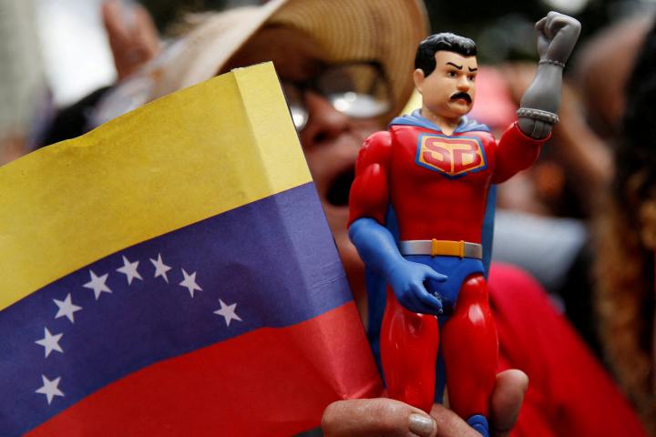 Un simpatizante del presidente venezolano, Nicolás Maduro, sostiene una figura de Super Bigote, el superhéroe inspirado en el mandatario, durante un acto en el Palacio de Miraflores, el 1 de diciembre de 2025.