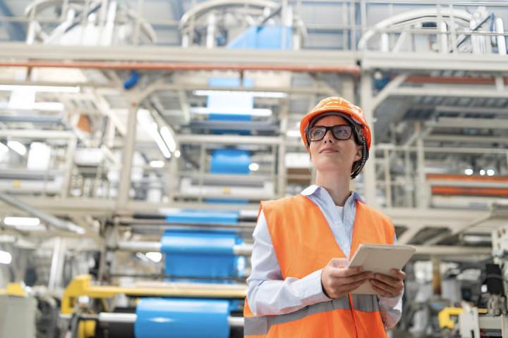 Una ingeniera que viste un chaleco y un casco de color naranja brillante
