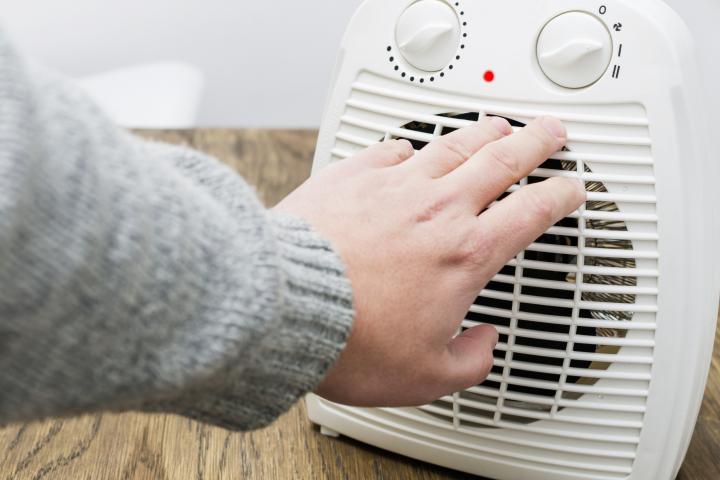 Una persona se calienta con un ventilador de radiador