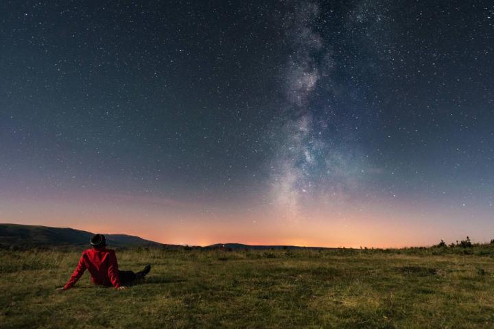Un joven tumbado en la hierba contemplando la Vía Láctea
