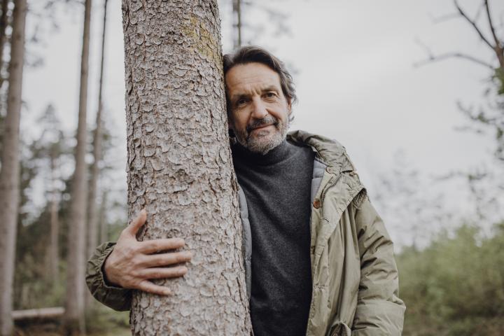 Excursionista maduro abrazando el tronco de un árbol