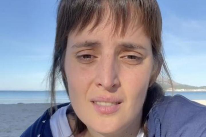 Captura de Florencia Conforti sentada en la arena hablando a cámara con el mar al fondo.