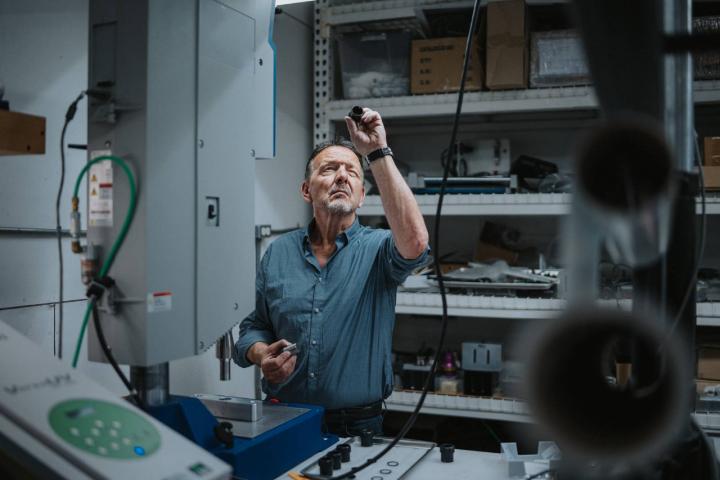 Hombre examinando el equipo mientras usa la prensa de perforación