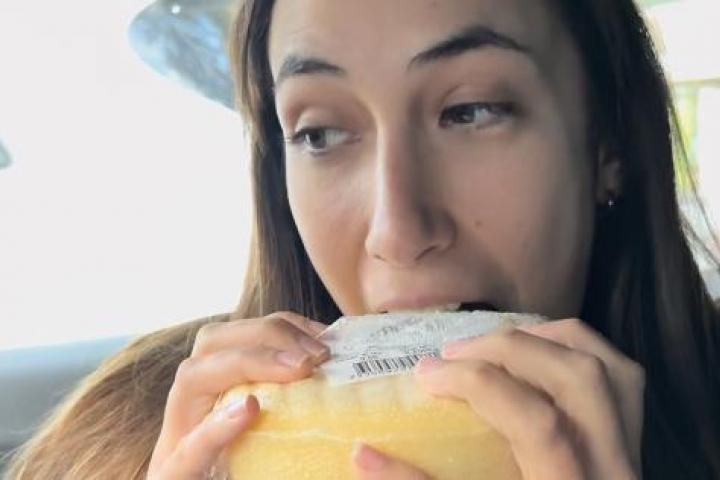 Joven dando un mordisco a un queso Arzúa-Ulloa en un coche mientras graba un vídeo para TikTok.