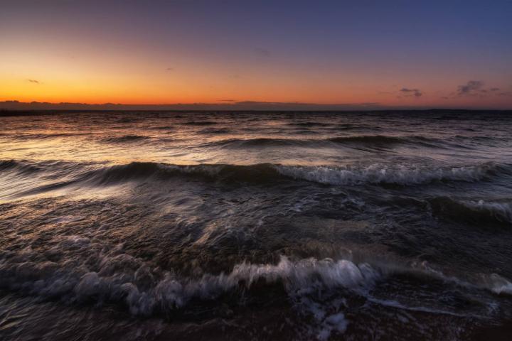 Olas en tiempo de tormenta en un gran lago embravecido a la cálida luz del amanecer vespertino