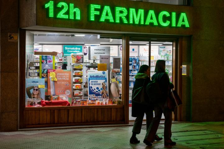Unos peatones cruzan ante una farmacia, en Madrid, en una imagen de marzo de 2022.