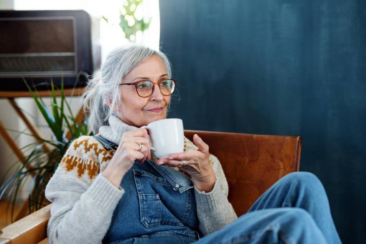 Mujer con café sentada en el interior de su casa, relajándose