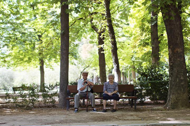 Dos ancianos sentados en un banco de un parque en Madrid