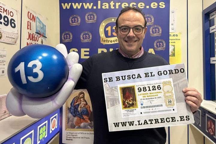 El lotero Jesús Ibáñez con el cartel informativo de 'Se busca el décimo'.