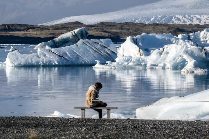 Una mujer descansando cerca de la orilla del lago Jökulsárlón, en Islandia