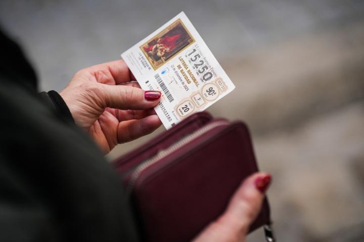 Una persona con un décimo de la Lotería de Navidad.
