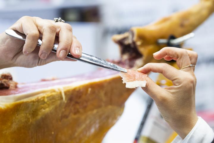 Una persona cortando jamón serrano.