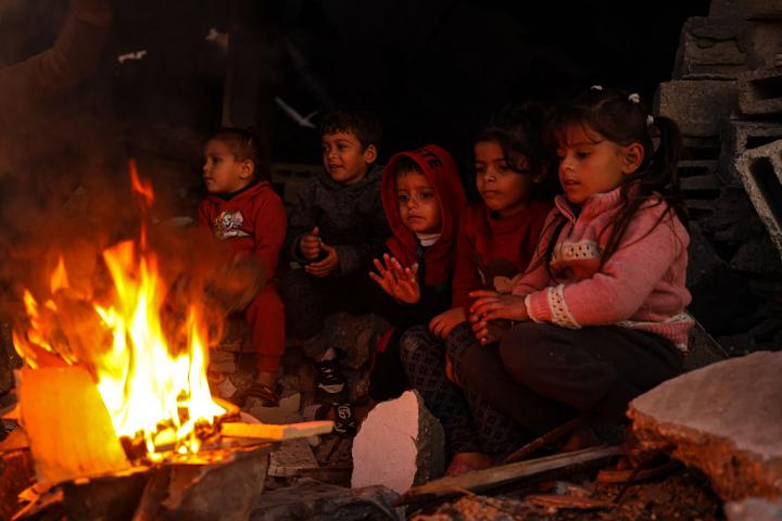 Unos niños intentan calentarse junto a las fogatas mientras los palestinos en Jabalia, en el norte de Gaza, entre los escombros dejados por los ataques israelíes, el 17 de diciembre de 2025.