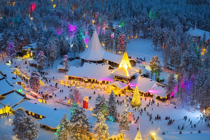 alt="alt="Árbol de Navidad y luces de colores en el pueblo de Papá Noel cubierto de nieve en una noche de invierno, Rovaniemi, Laponia, Finlandia""