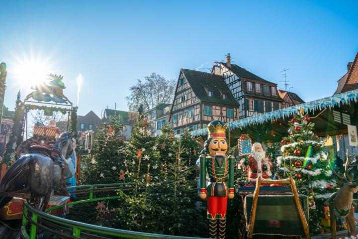 alt="alt="Vista panorámica de casas y negocios franceses de estilo alsaciano de colores vibrantes junto al canal de Colmar.""