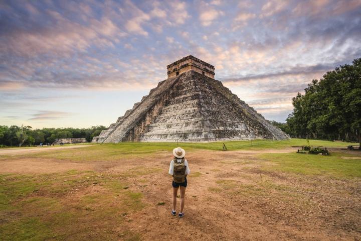 Mujer admirando la pirámide de Kukulkán en Chichén Itzá al amanecer, México.