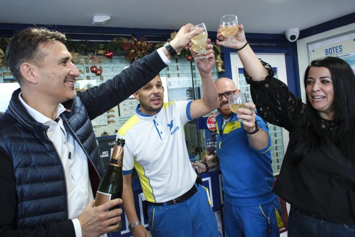 Daniel Rodríguez y Alexandra López, los propietarios del punto de venta de lotería situado en la gasolinera El Bohío, en el municipio tinerfeño de La Matanza, celebran junto a dos trabajadores este lunes después de conocer que el local ha repartido el segundo de los cuartos premios de la Lotería de Navidad.