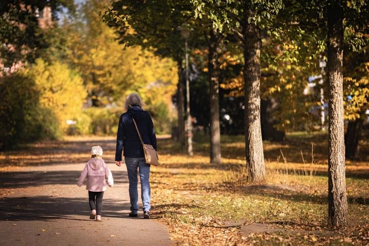 Una abuela paseando con su nieta de la mano en un parque