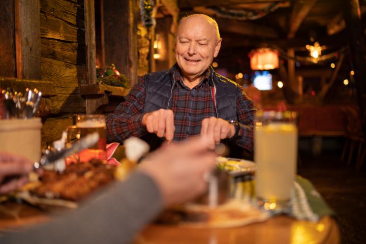 Señor mayor cortando un filete en una comida de Navidad.