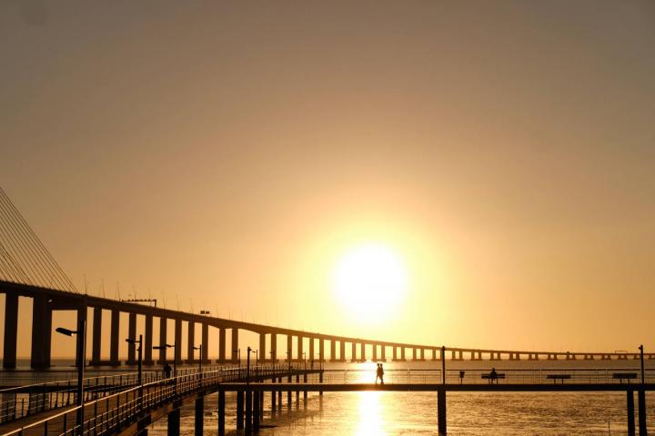 Amanecer en el puente Vasco da Gama con siluetas en la pasarela del río Tajo