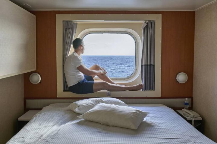 Hombre contemplando el océano desde el camarote de un crucero