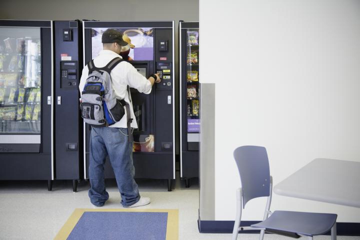 Un joven usando una máquina expendedora.