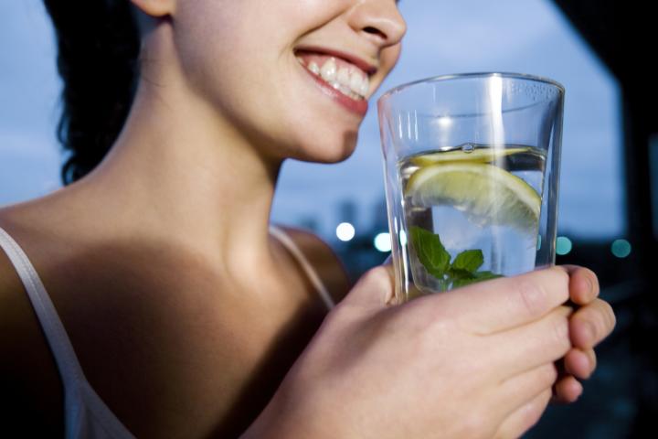 Persona bebiendo agua con limón, una práctica habitual vinculada a mitos sobre nutrición y bienestar.