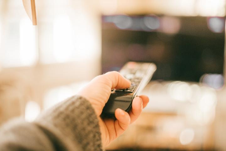 Una persona usando el mando de televisión para cambiar de canal.