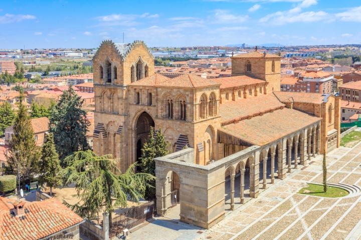 alt="alt="Ávila es conocida por sus intactas murallas medievales. Sus fortificaciones, compuestas por 82 torres semicirculares y nueve puertas, son las más completas de España. Las murallas del siglo XII se extienden a lo largo de 2,5 km sobre los restos de antiguas almenas romanas y musulmanas, y se encuentran entre los perímetros defensivos medievales mejor conservados del mundo. El casco antiguo de Ávila, con sus iglesias extramuros, fue declarado Patrimonio de la Humanidad por la UNESCO en 1985.""