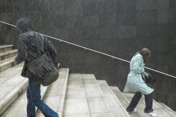 Dos personas subiendo y bajando escaleras bajo la lluvia, vista lateral -