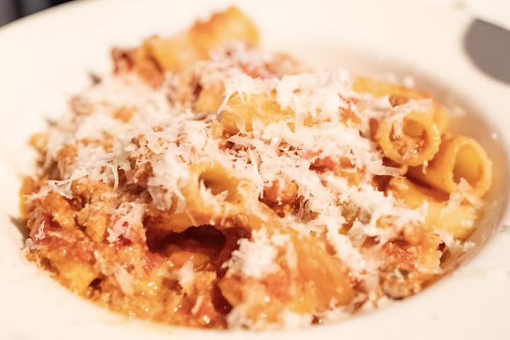 Primer plano de un tazón de fideos de pasta con salsa boloñesa y queso.