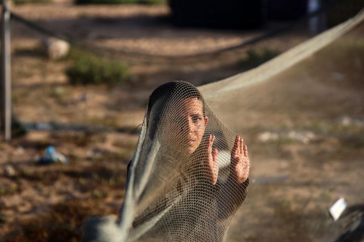 Un niño palestino se entretiene con una red de pesca en el puerto de la ciudad de Gaza, en una zona de refugio, el 9 de mayo de 2025.