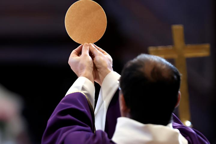 Un sacerdote oficiando una misa y alzando el pan ácimo