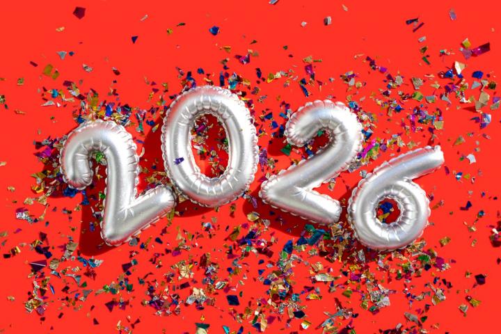 Globos plateados con el número 2026 y confeti sobre un fondo rojo vibrante