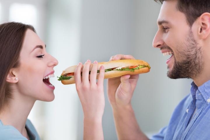 Una pareja de hombre y mujer compartiendo un sándwich
