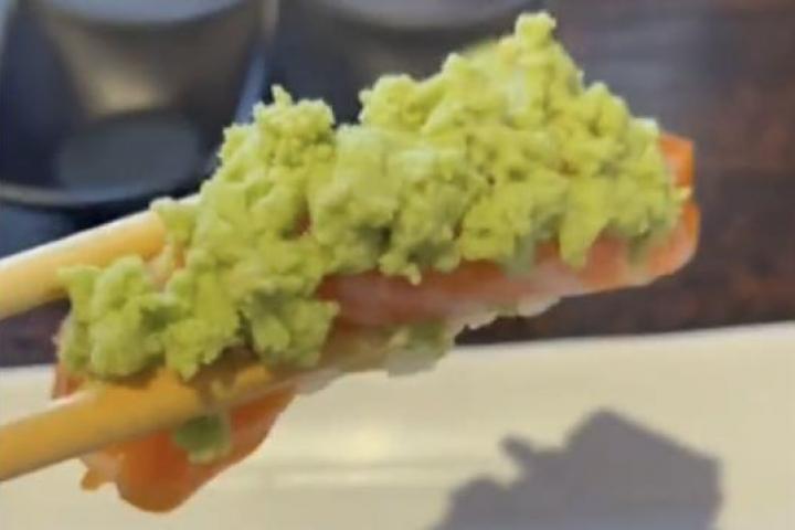 Nigiri de salmón con pasta verde de wasabi falso servido en un restaurante de sushi