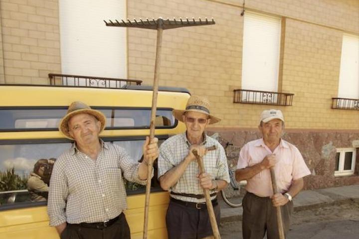 Tres vecinos posan con sus herramientas tras una jornada de hacenderas.