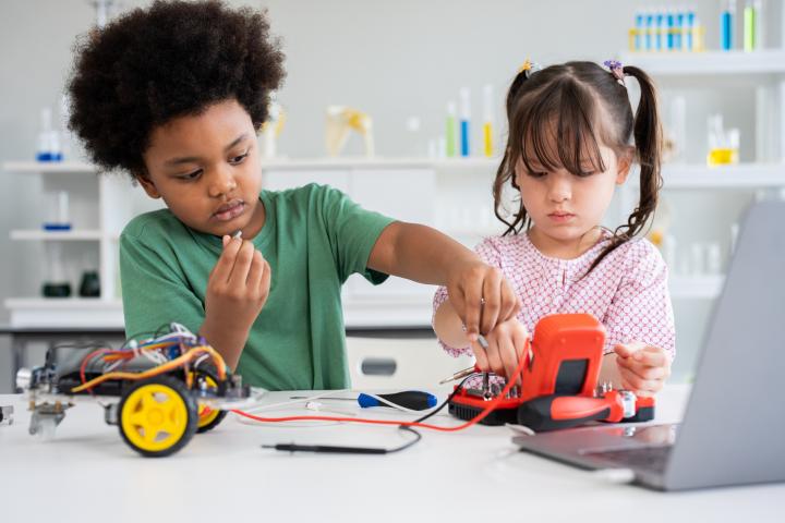 alt="alt="Niño y niña concentrados creando un coche robot en el laboratorio de la escuela.""