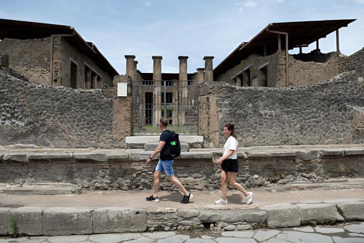 Dos turistas visitando el Parque Arqueológico de Pompeya, caminando entre antiguas ruinas