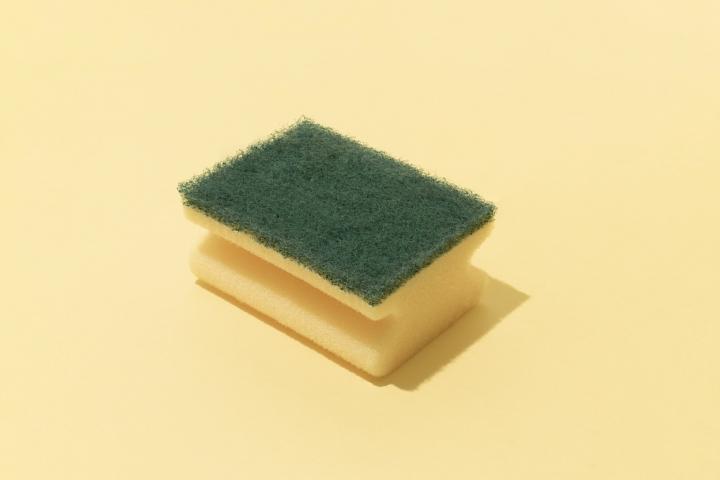 Estropajo de cocina limpio utilizado como truco para atrapar pelos y suciedad en la lavadora durante la colada.