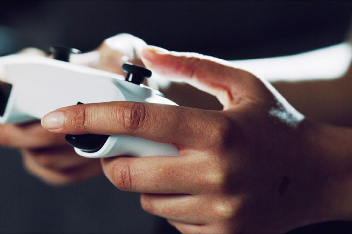 Manos de una persona sosteniendo un mando de color blanco de una consola de videojuegos