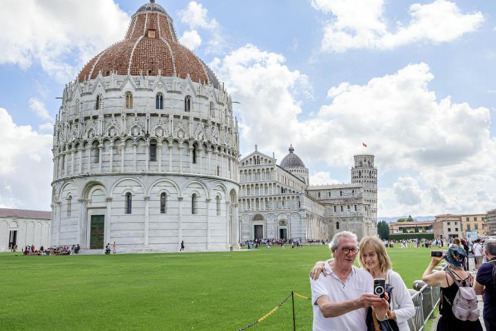 Una pareja de jubilados haciéndose una foto en la Catedral Católica de Pisa