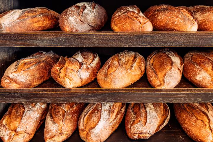 Varias hogazas de pan rústico en estantes de madera de una panadería