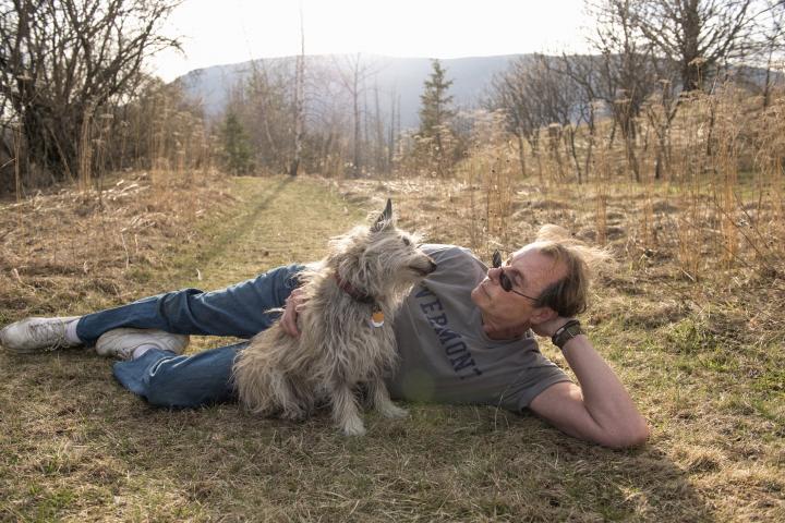 Hombre maduro tumbado en el suelo con su Carin Terrier sentado a su lado