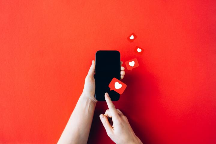 Una persona con un móvil del que surgen unos corazones