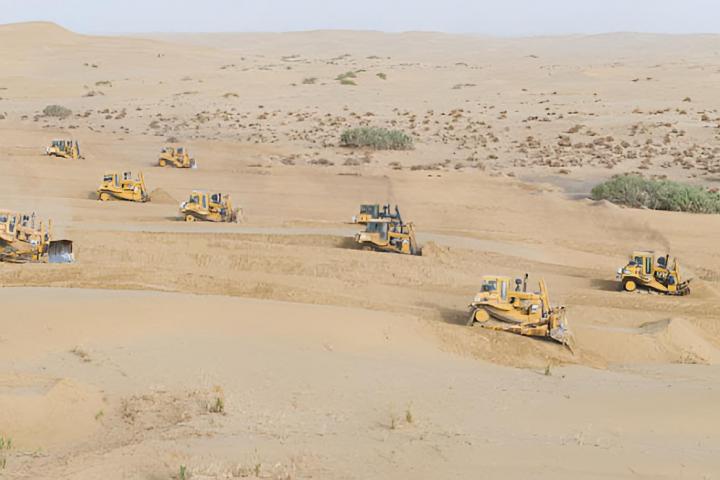 Maquinaria de gran escala nivelando dunas de arena en el desierto de Taklimakan en Xinjiang, China